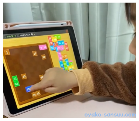 トドさんすうで3歳児が100マスパズルで数字を学んでいる画像
